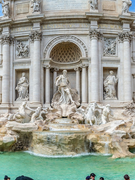 Trevi Fountain with sculptures and tourists in Rome, Italy.