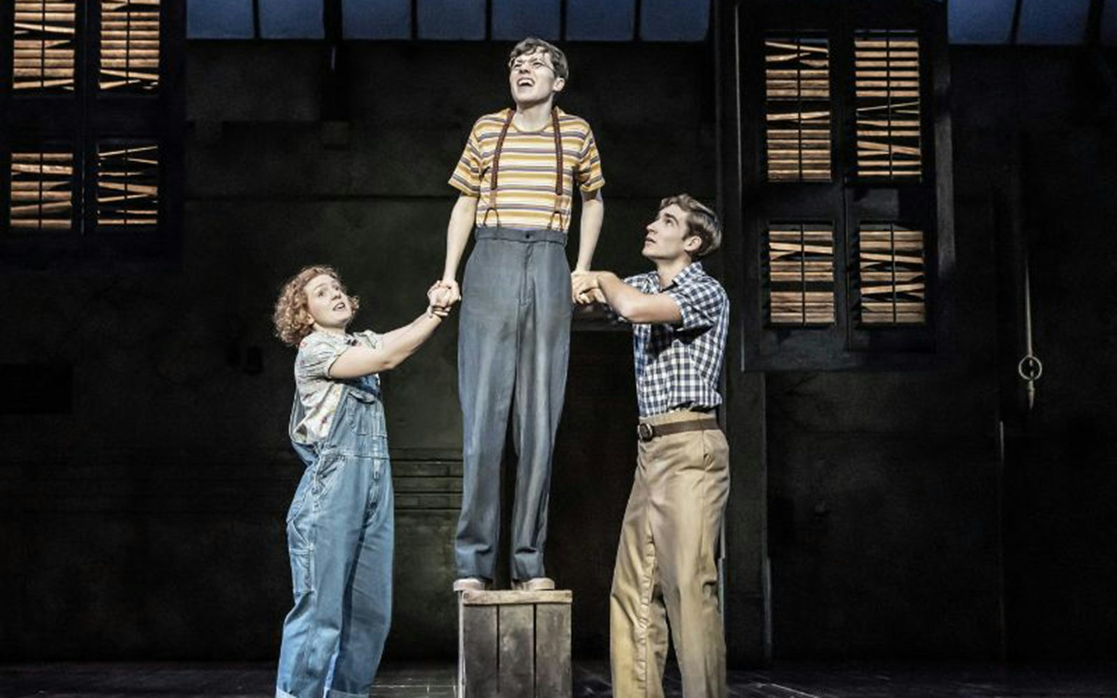 Three actors perform a scene from "To Kill A Mockingbird" on stage.