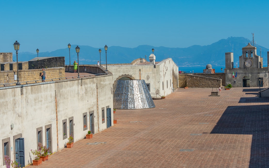 Courtyard of Castel Sant'Elmo in Naples with distant mountain view.