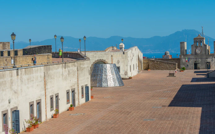 Courtyard of Castel Sant'Elmo in Naples with distant mountain view.
