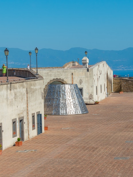 Courtyard of Castel Sant'Elmo in Naples with distant mountain view.