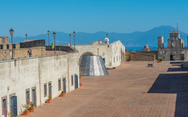 Courtyard of Castel Sant'Elmo in Naples with distant mountain view.
