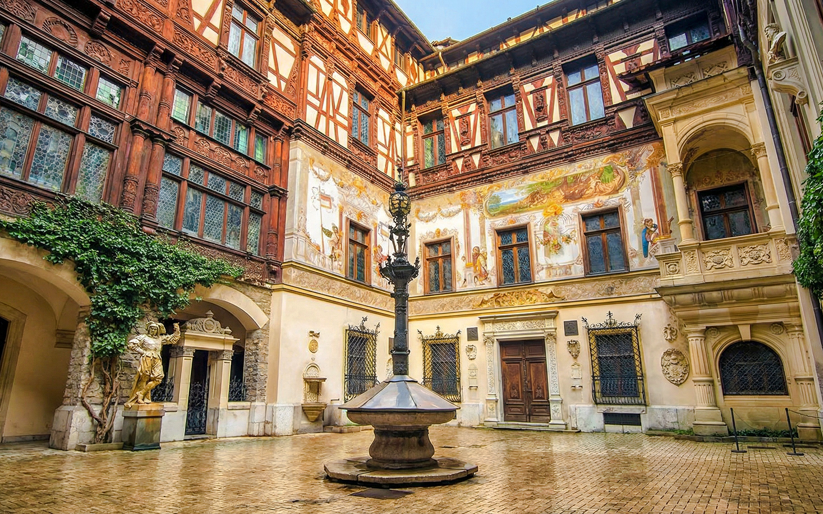 Inner courtyard of Peleș Castle with ornate architecture and central fountain, Sinaia, Romania.