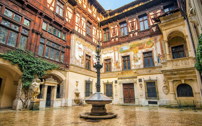 Inner courtyard of Peleș Castle with ornate architecture and central fountain, Sinaia, Romania.