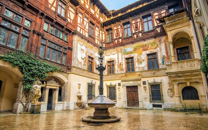 Inner courtyard of Peleș Castle with ornate architecture and central fountain, Sinaia, Romania.