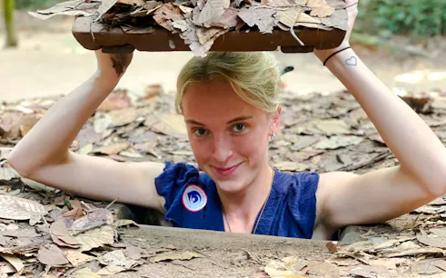 Person emerging from a hidden entrance at Cu Chi Tunnels, Tay Ninh.
