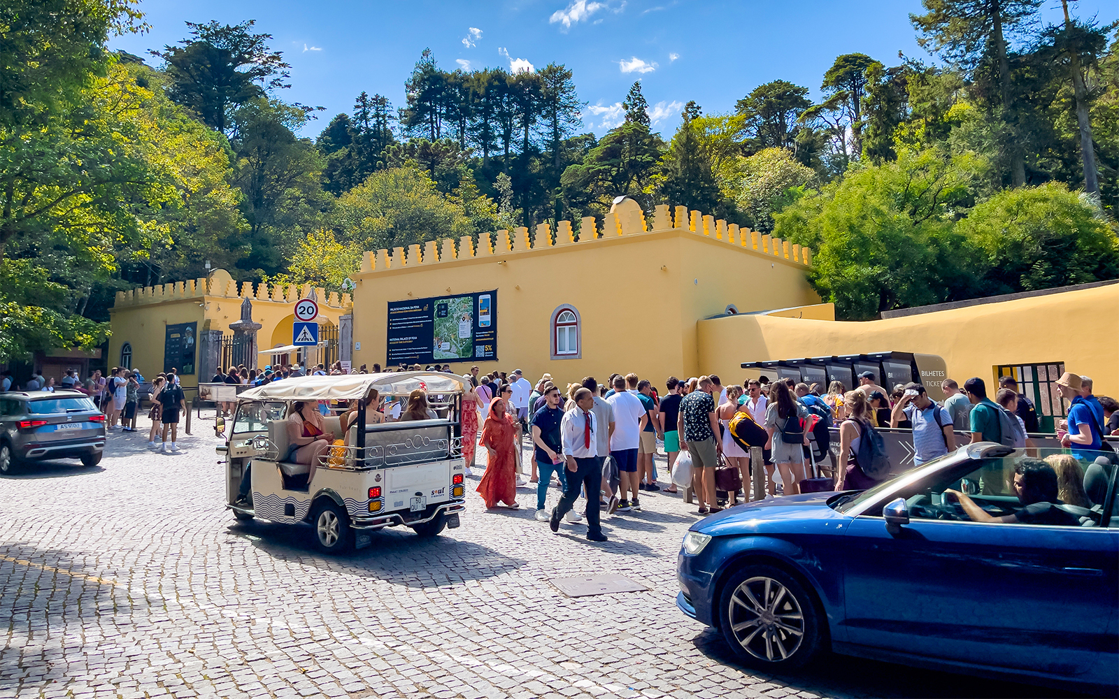 Crowd outside Sintra National Palace entrance with parked cars, Portugal.