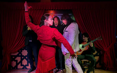 Flamenco dancers performing at Tablao Jardines de Zoraya with guitarist in background.