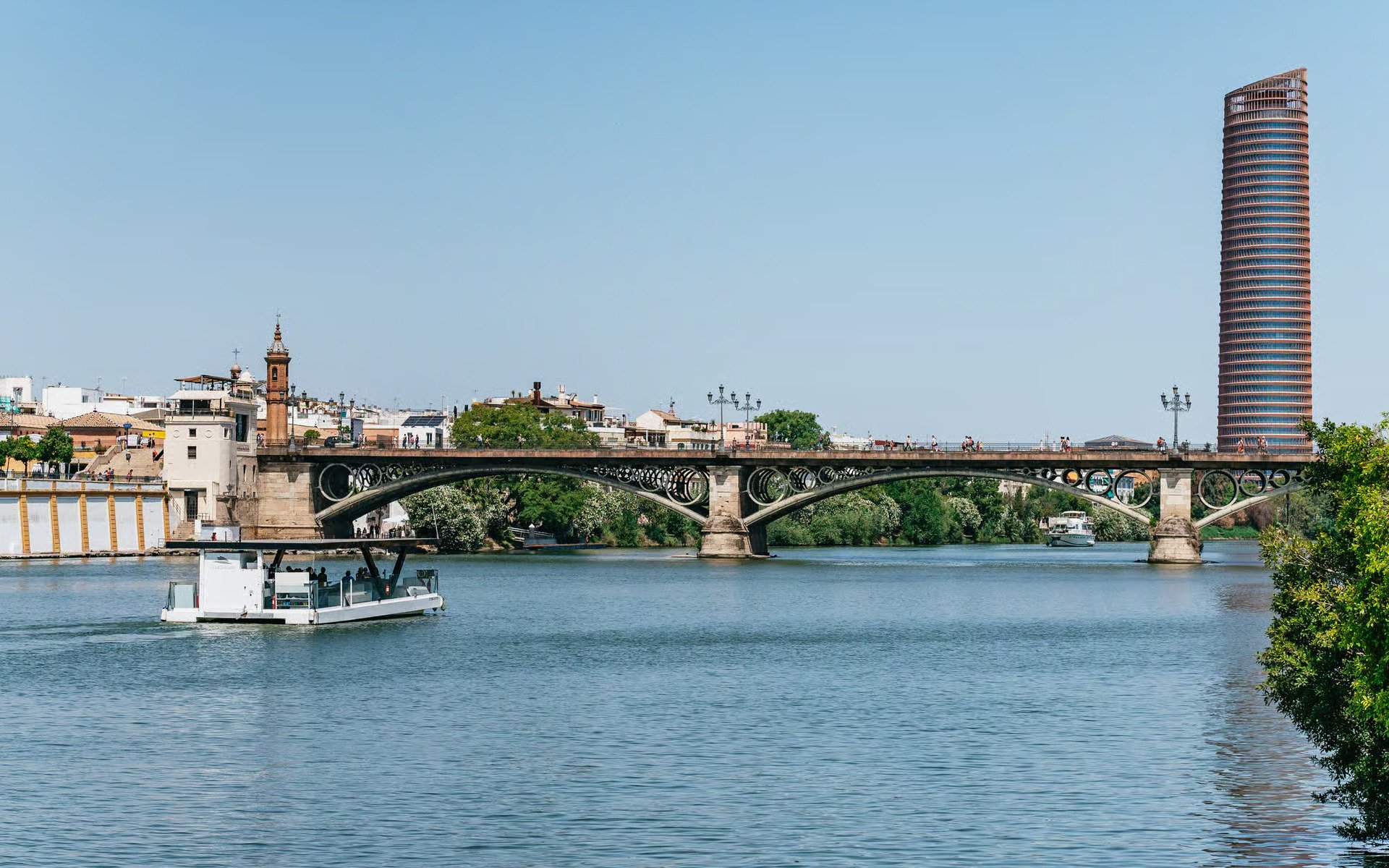 Cruise on Guadalquivir River passing Triana Bridge in Seville, Spain.