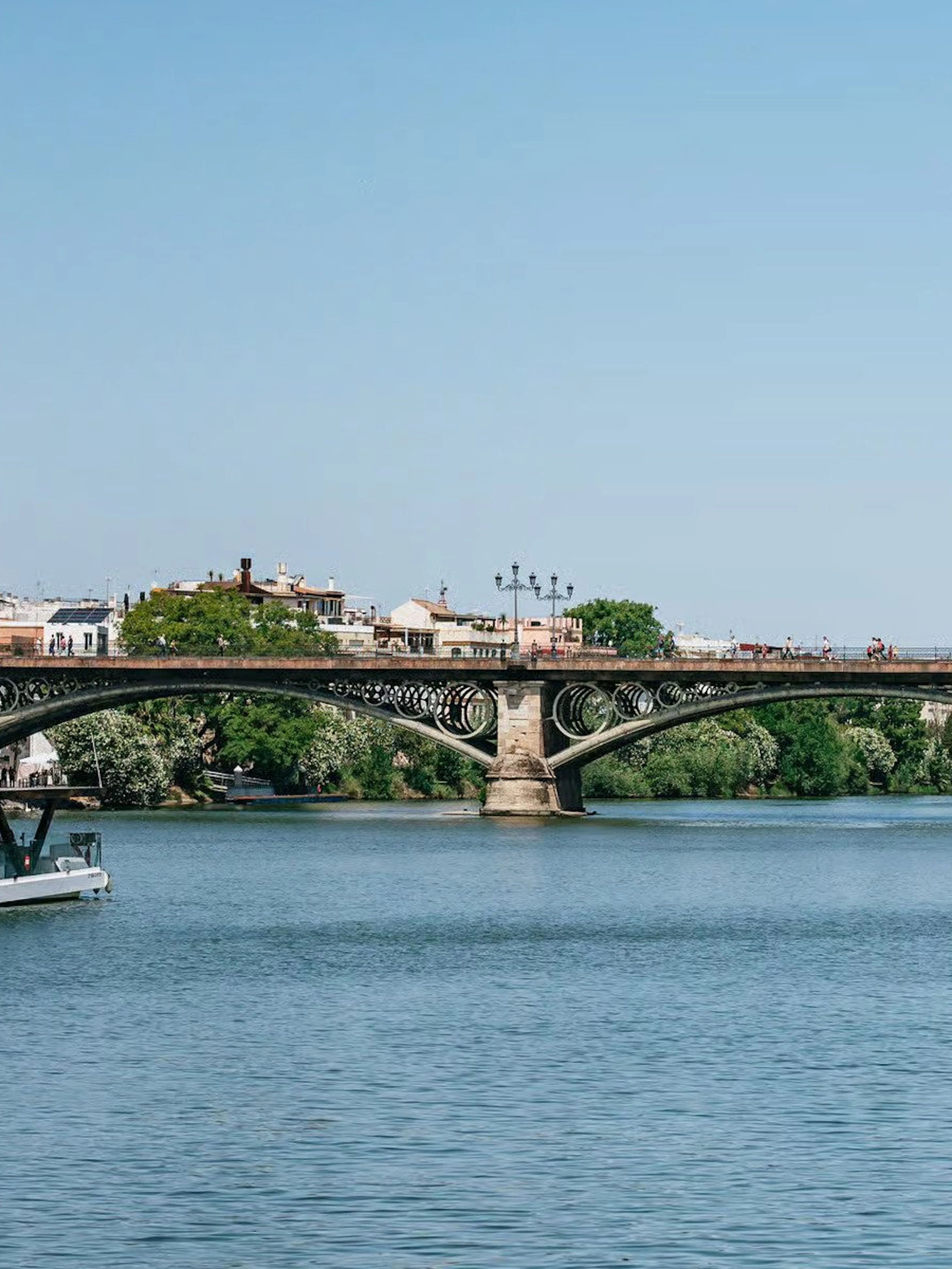 Cruise on Guadalquivir River passing Triana Bridge in Seville, Spain.