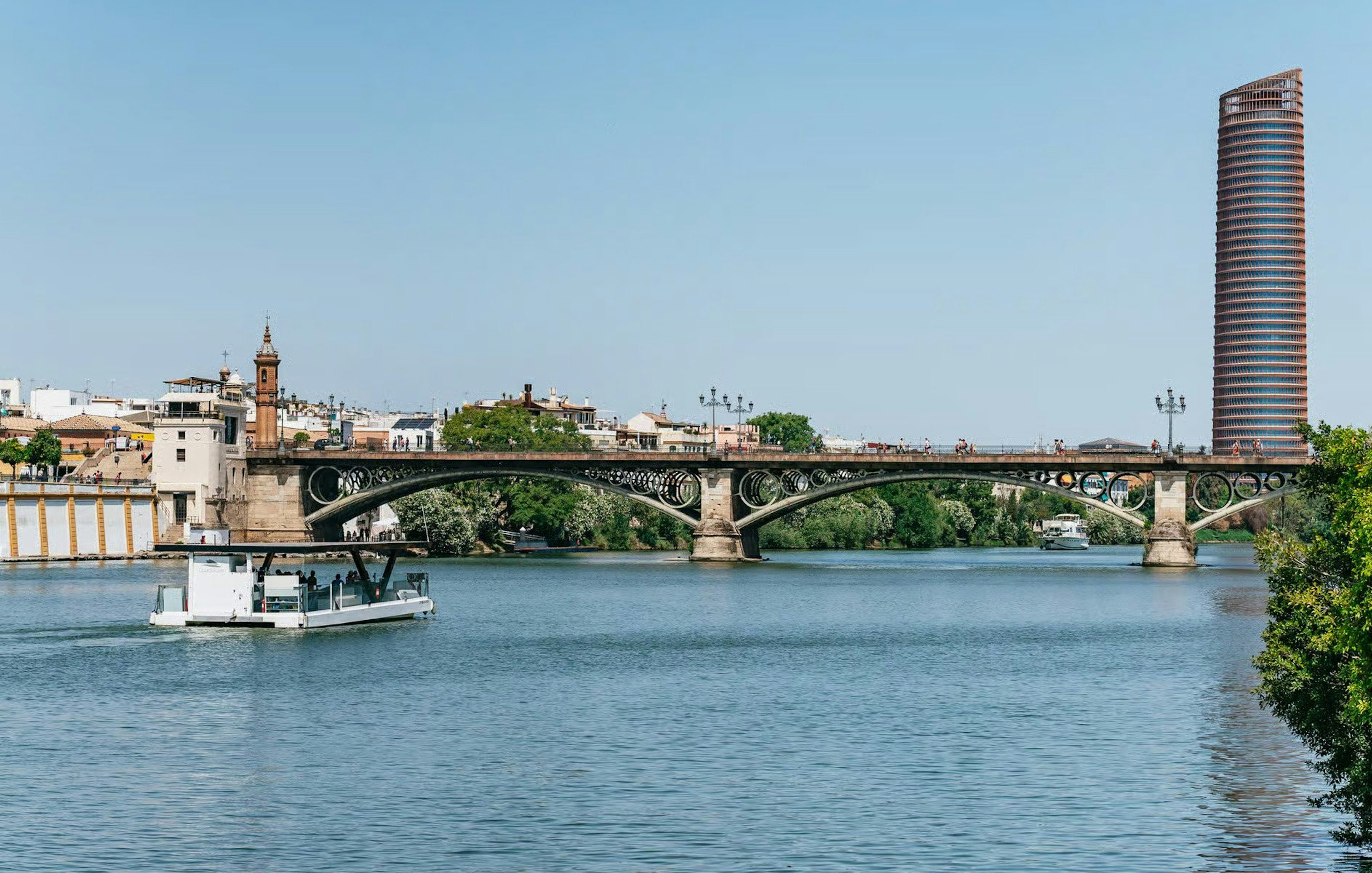 Cruise on Guadalquivir River passing Triana Bridge in Seville, Spain.