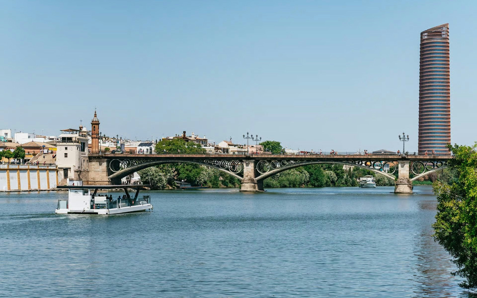 Cruise on Guadalquivir River passing Triana Bridge in Seville, Spain.