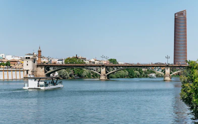 Cruise on Guadalquivir River passing Triana Bridge in Seville, Spain.