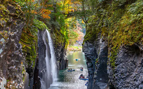 Boats in Takachiho Gorge with waterfall and bridge, Miyazaki, Japan.