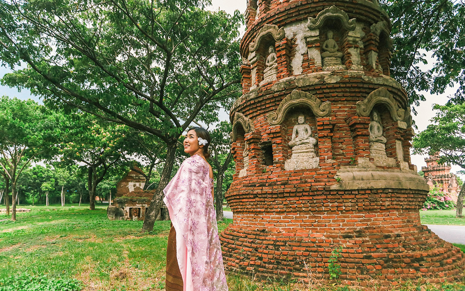 Person in traditional attire near ancient brick stupa with Buddha statues, Ancient City tour.