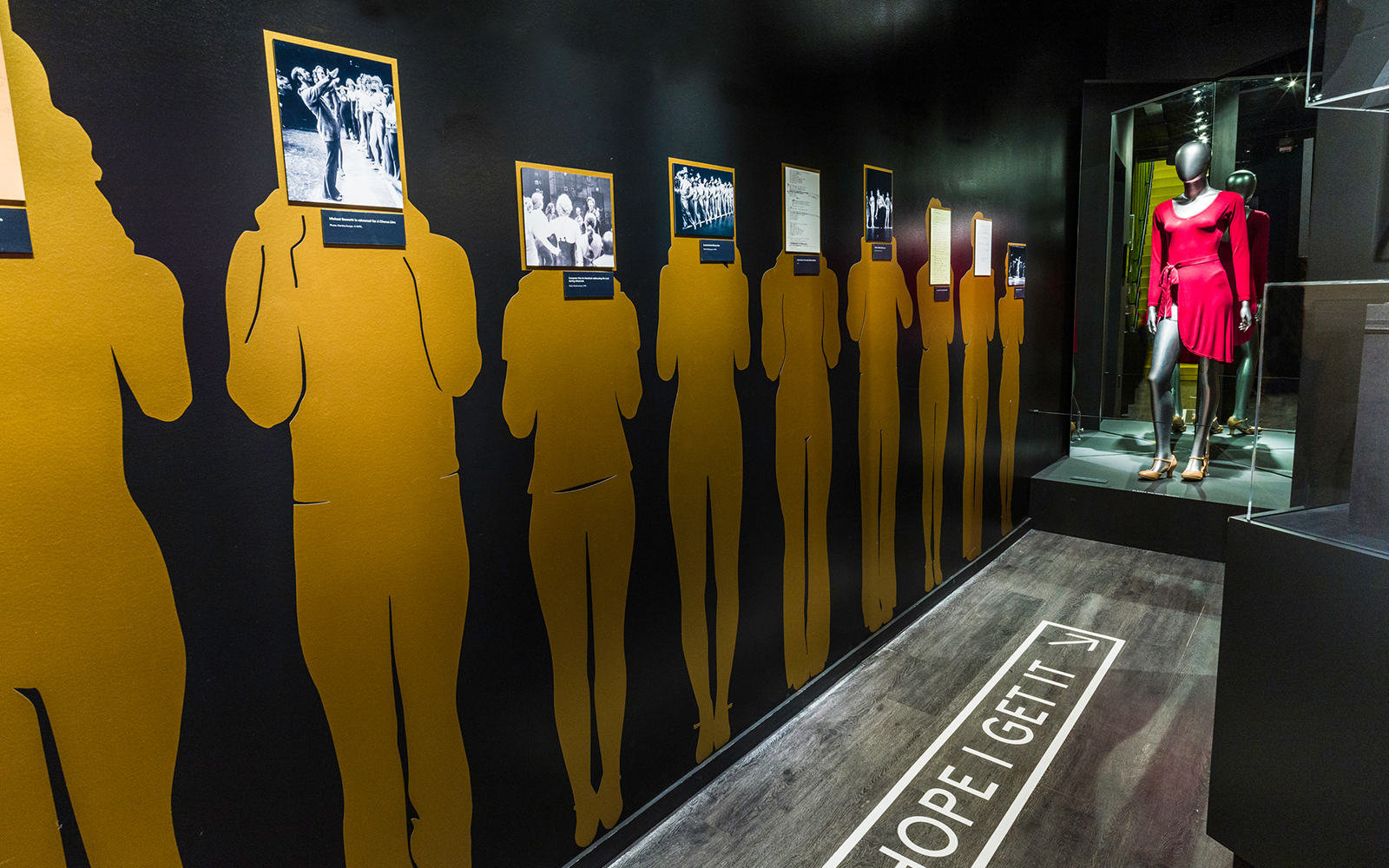 Silhouettes with historical Broadway photos and mannequin in red dress at The Museum of Broadway.