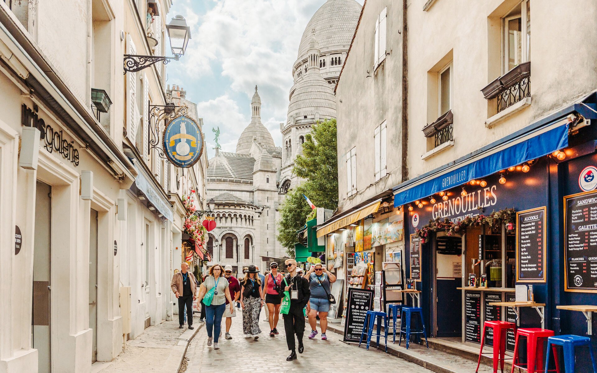 Tourists walking in Montmartre with Sacré-Cœur Basilica in the background, Paris, France.