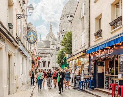 Tourists walking in Montmartre with Sacré-Cœur Basilica in the background, Paris, France.