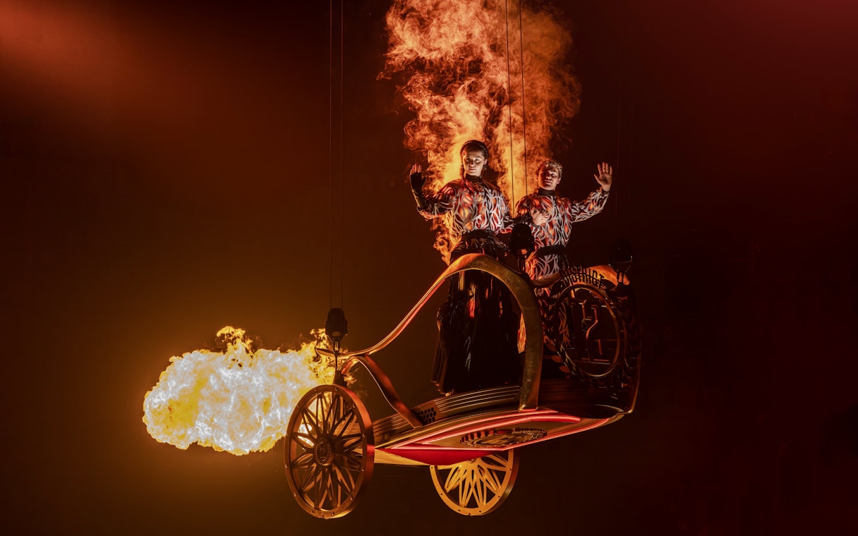 Performers in fiery costumes on stage during Hunger Games West End show.