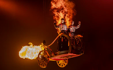 Performers in fiery costumes on stage during Hunger Games West End show.