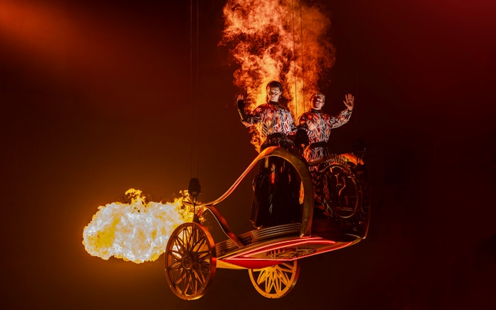 Performers in fiery costumes on stage during Hunger Games West End show.