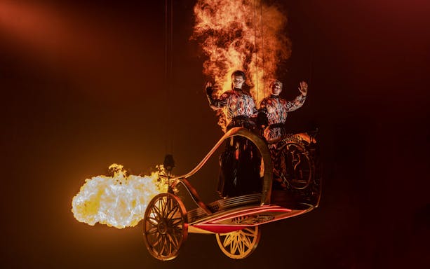 Performers in fiery costumes on stage during Hunger Games West End show.