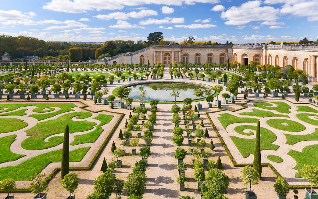 Versailles Palace gardens with manicured hedges and central fountain on a day trip to Paris.