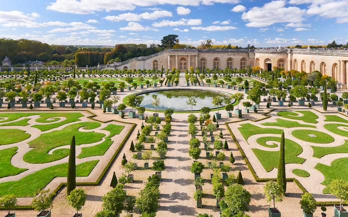 Versailles Palace gardens with manicured hedges and central fountain on a day trip to Paris.