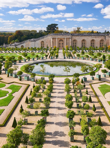 Versailles Palace gardens with manicured hedges and central fountain on a day trip to Paris.