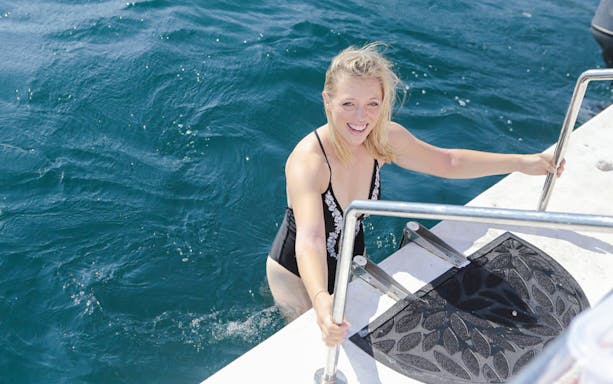 Female guest climbing boat ladder during Kotor tour.