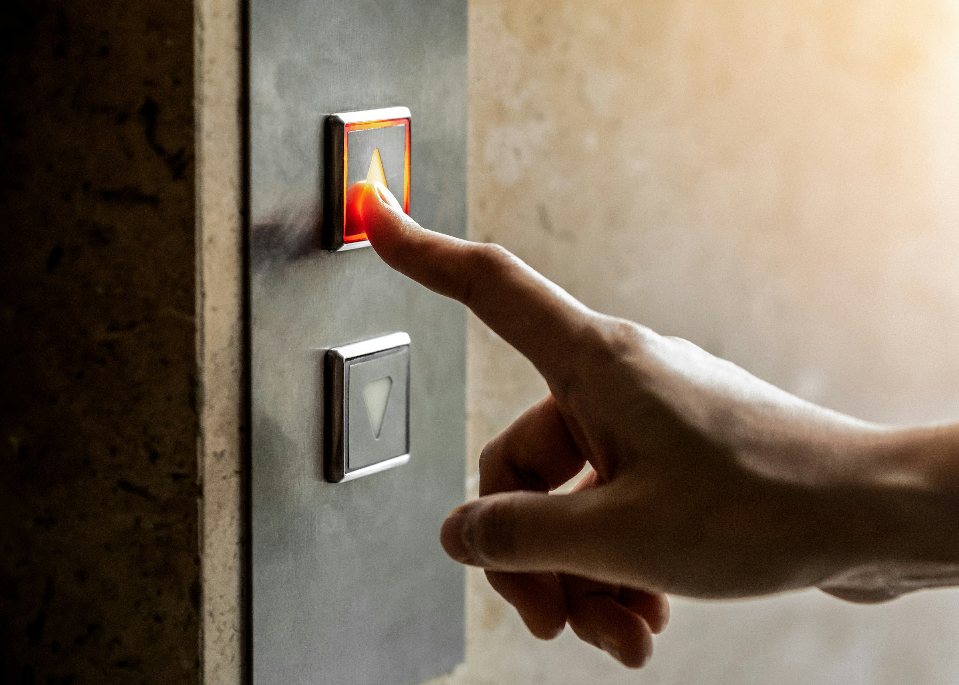 Finger pressing an elevator button to go up.