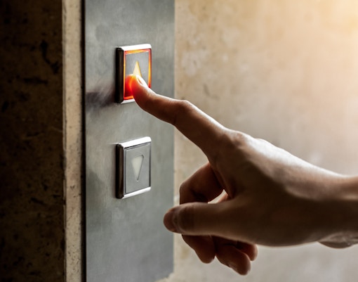 Eine Person drückt auf den Rufknopf eines Aufzugs