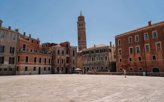 Venice square with historic buildings and a tall bell tower under a clear sky.
