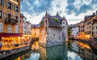 Annecy canal with historic buildings and evening lights reflecting on water.