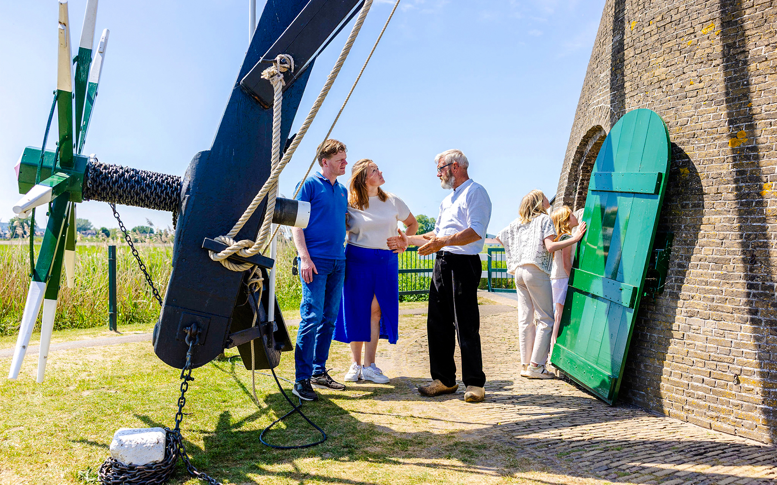 Family learning about windmills at Kinderdijk, Netherlands, with a guide explaining the mechanism.