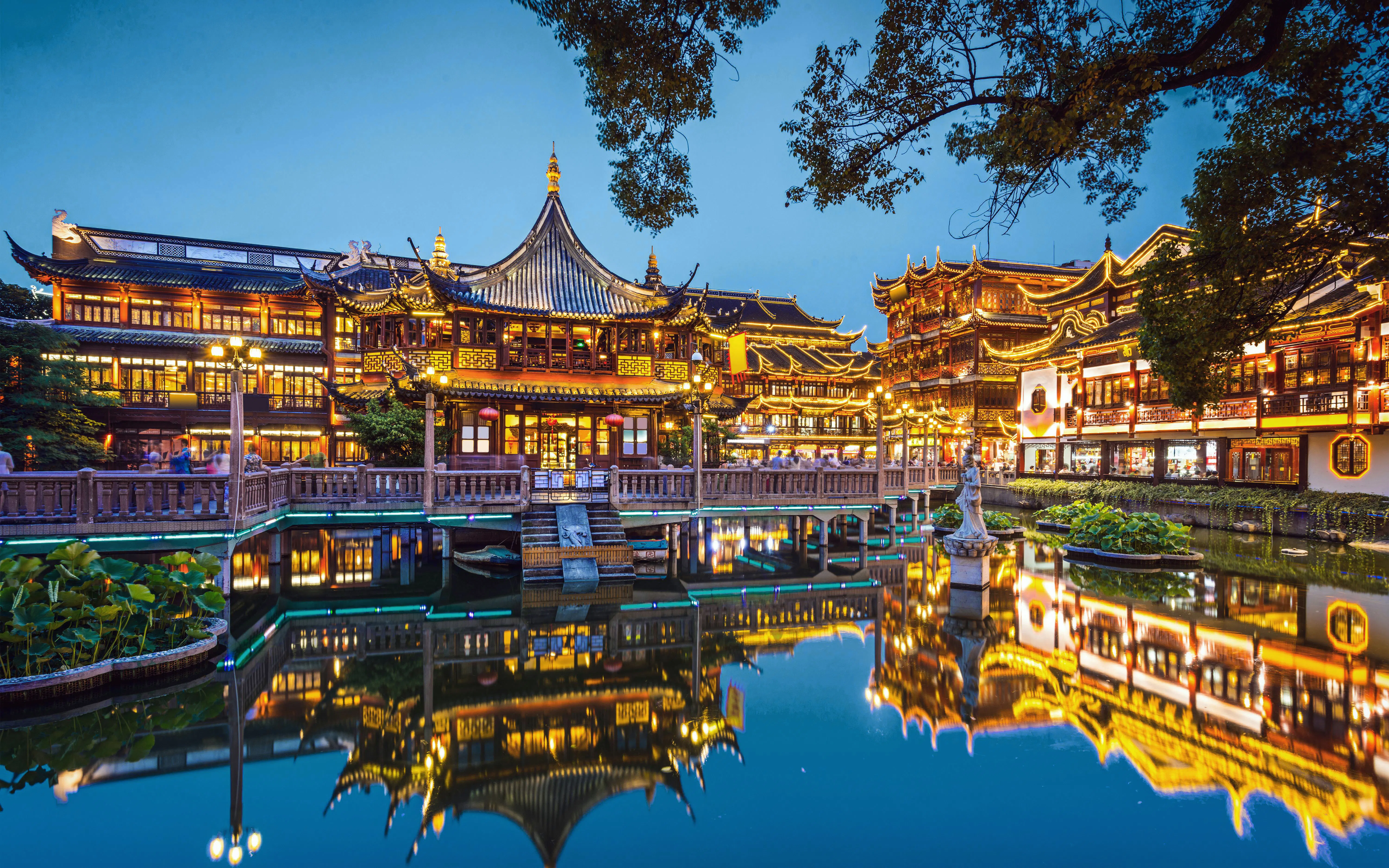 Yuyuan Gardens in Shanghai, China, illuminated at night with traditional architecture reflected in the pond.