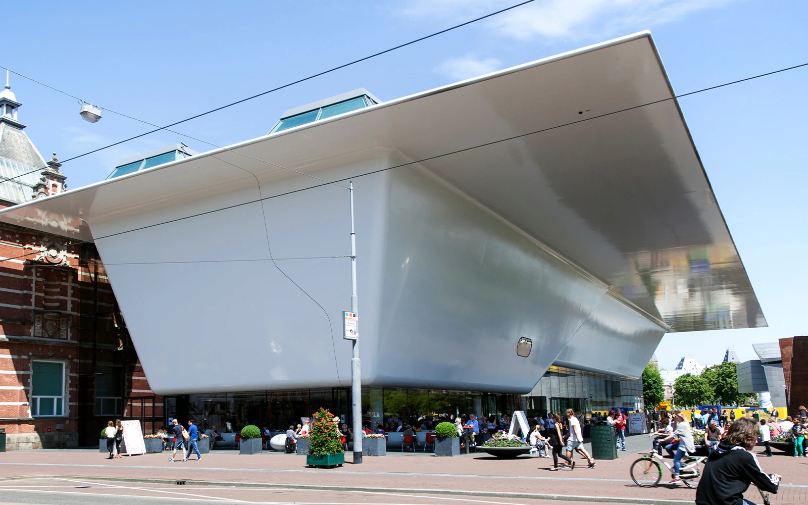 Stedelijk Museum entrance in Amsterdam with people walking and cycling nearby.
