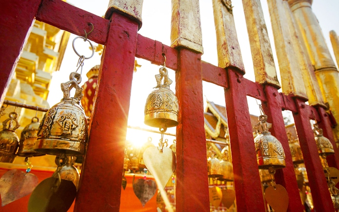 Golden bells on red fence at Doi Suthep, Chiang Mai, with sunlight.