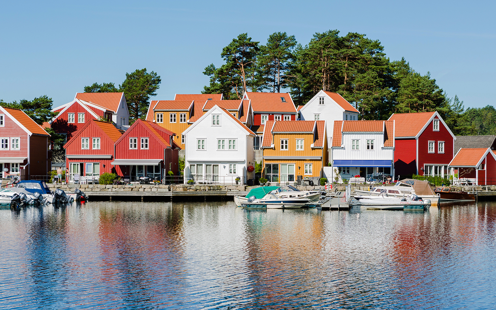 Colorful houses along the waterfront in Svennevik, Stockholm with boats docked nearby.