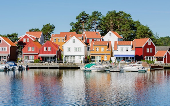 Colorful houses along the waterfront in Svennevik, Stockholm with boats docked nearby.