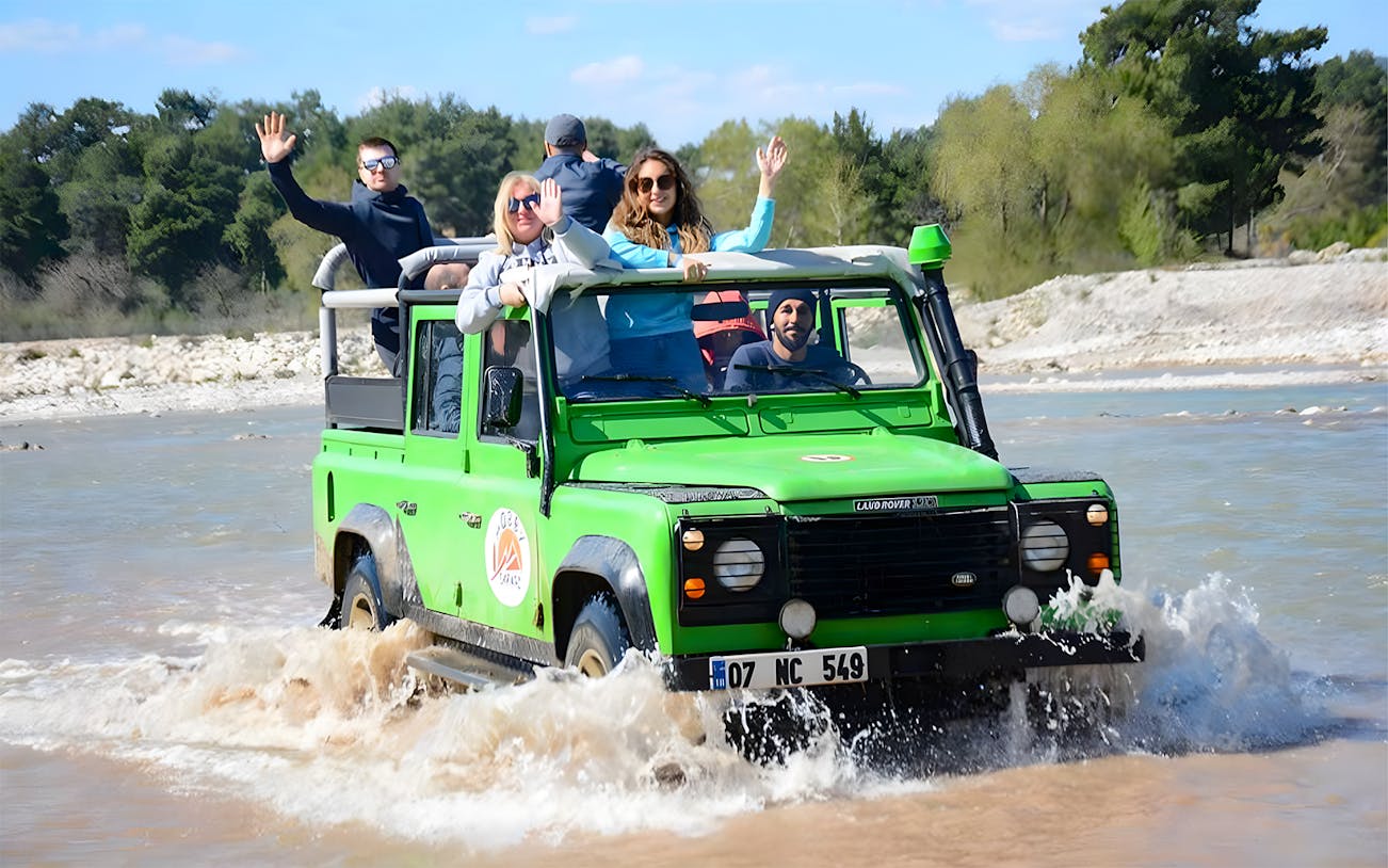Tourists in a green jeep crossing a river during the Kekova Sunken City tour in Demre.