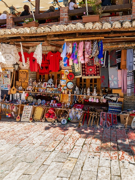 Market stall with traditional textiles and crafts in Kruja's old town market.