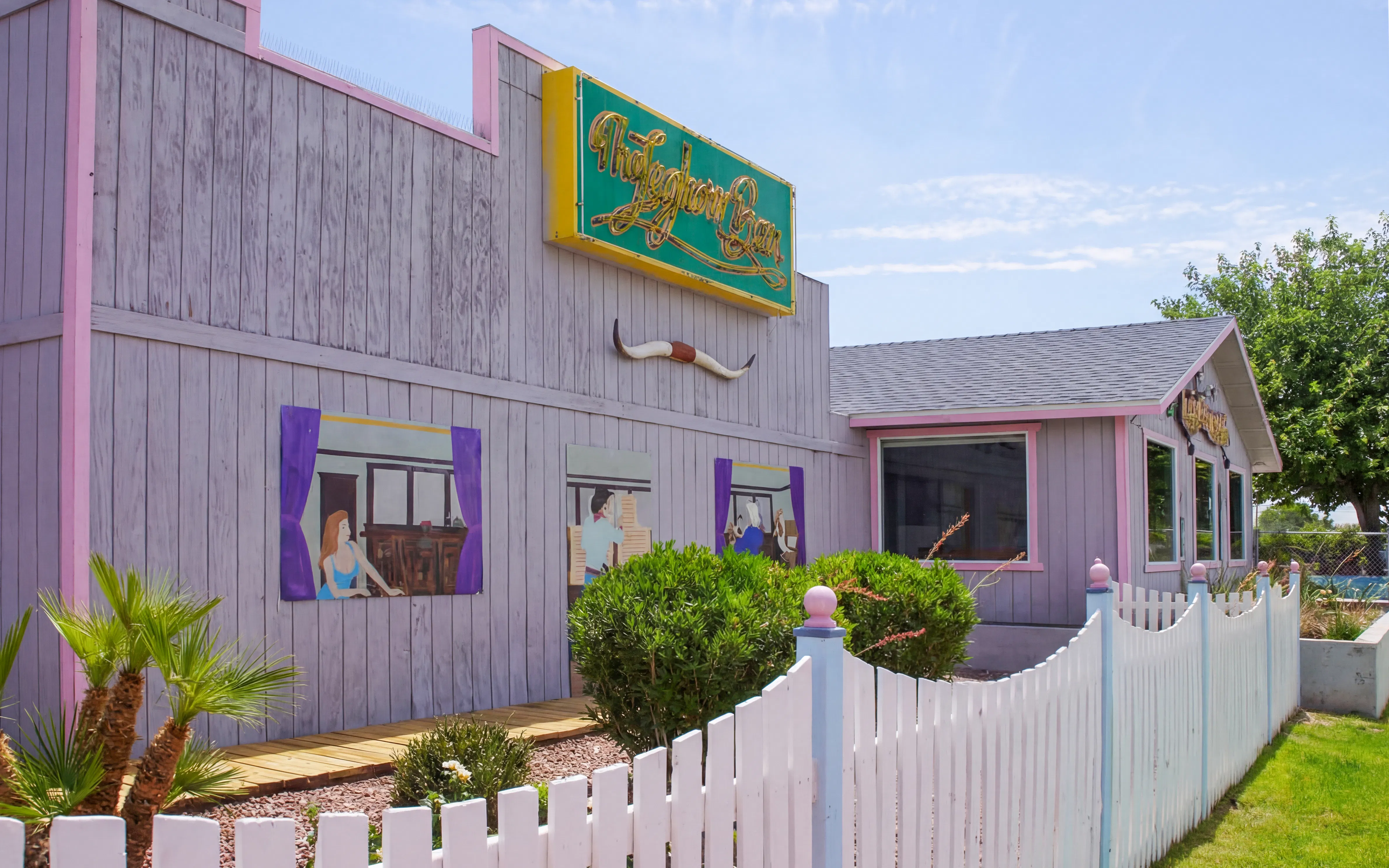 Leghorn Bar exterior with murals, white fence, and desert plants in Nevada.