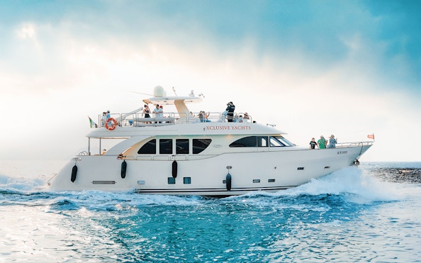 Luxury yacht cruising on blue waters with passengers enjoying the view.