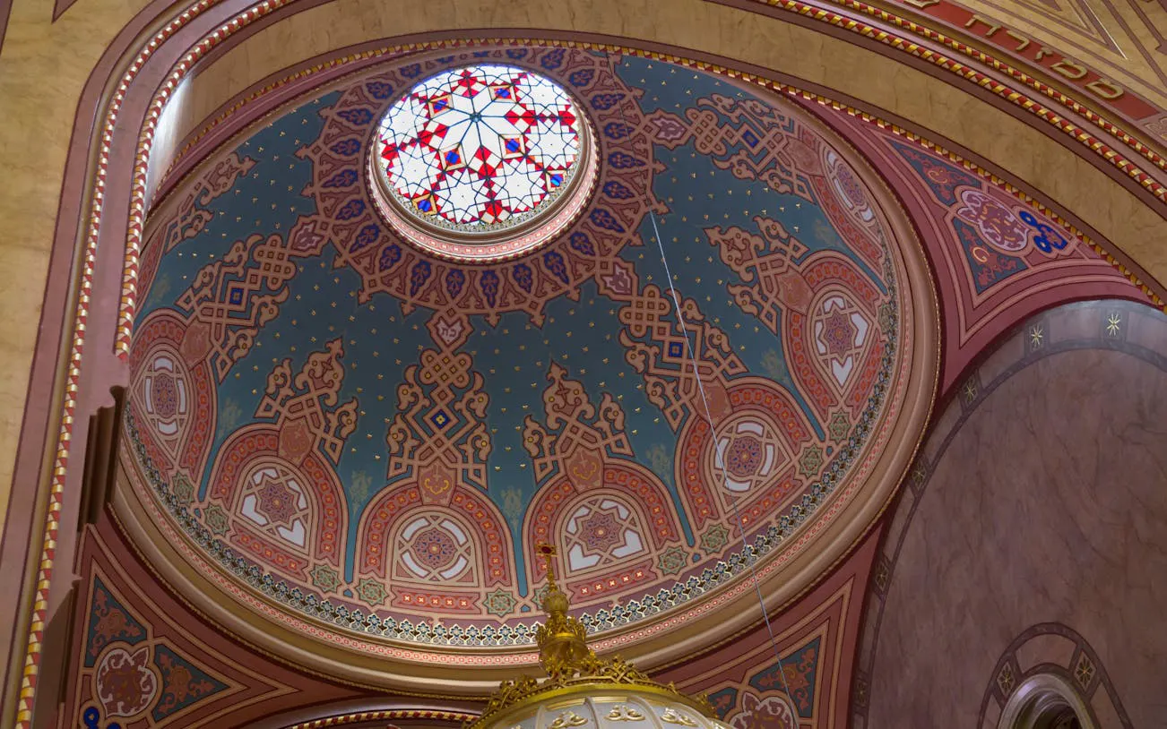 Dome interior of Dohány Street Synagogue in Budapest with intricate patterns and stained glass.