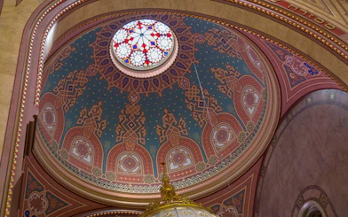 Dome interior of Dohány Street Synagogue in Budapest with intricate patterns and stained glass.