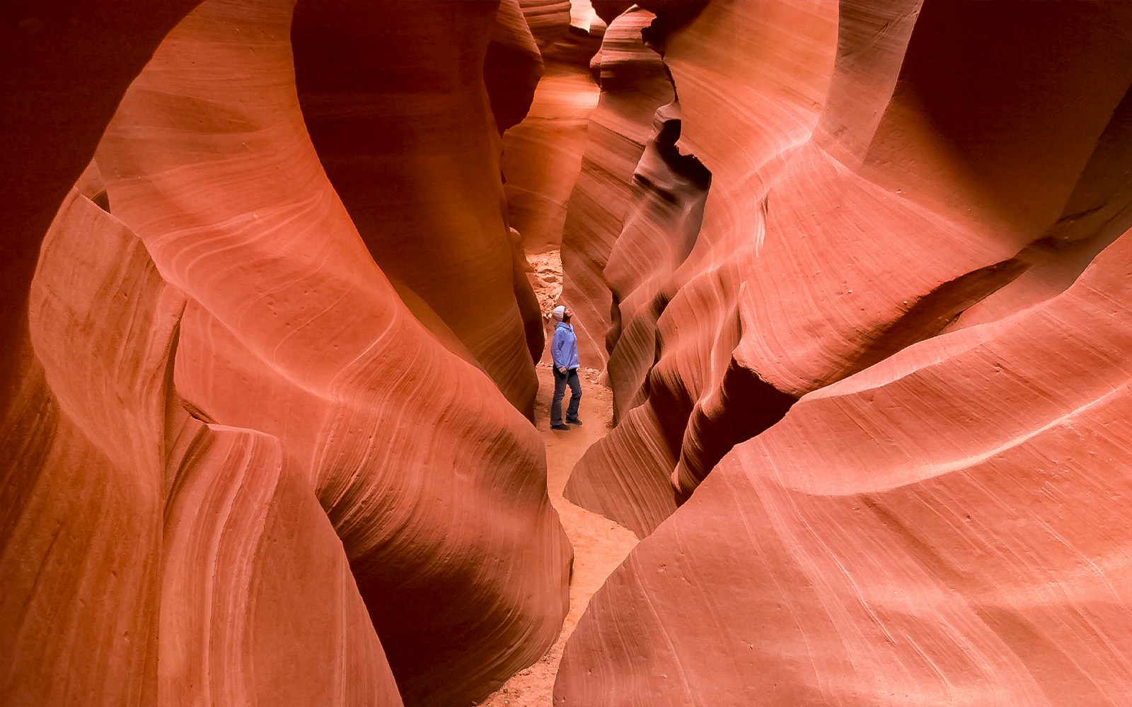 Person exploring narrow passage in Secret Antelope Canyon, southwest slot canyons.