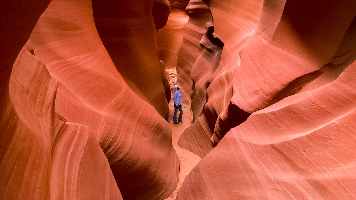 Person exploring narrow passage in Secret Antelope Canyon, southwest slot canyons.
