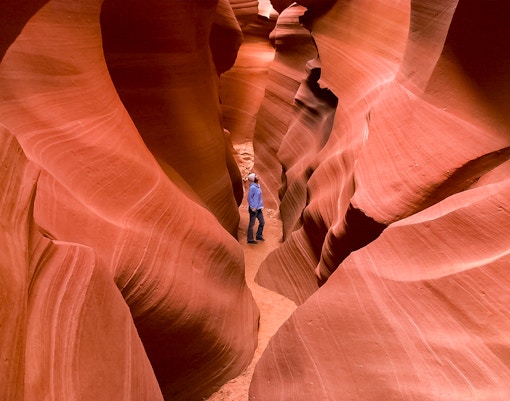Person exploring narrow passage in Secret Antelope Canyon, southwest slot canyons.