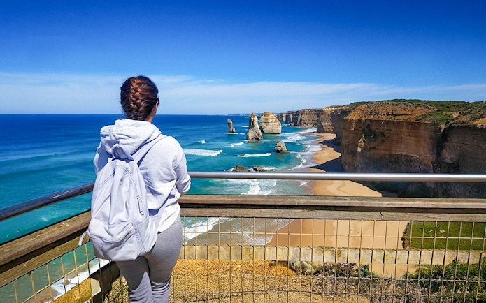 Woman at viewpoint overlooking 12 Apostles on Great Ocean Road, Australia.